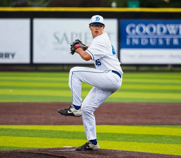 Austin delivering a pitch in a white uniform